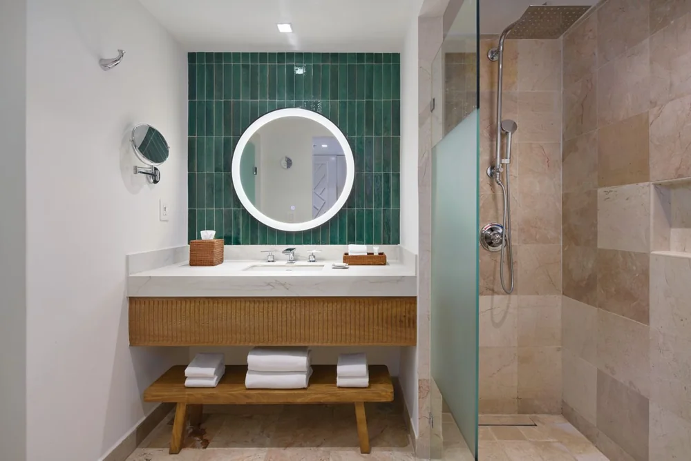 Espejo LED redondo NAALA en baño con azulejo verde