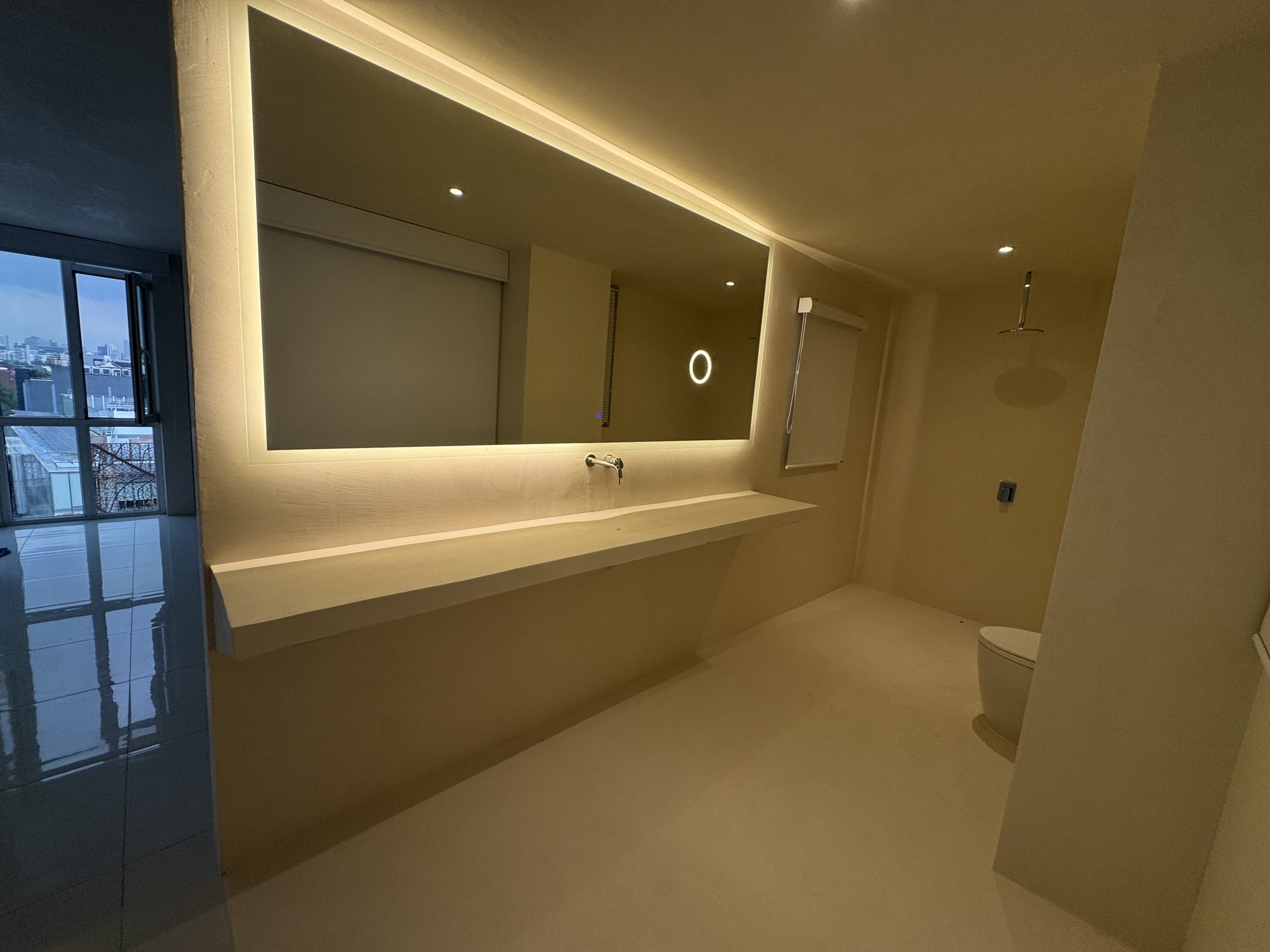 Espejo LED con luz cálida alrededor del cristal en baño con lavabo de concreto