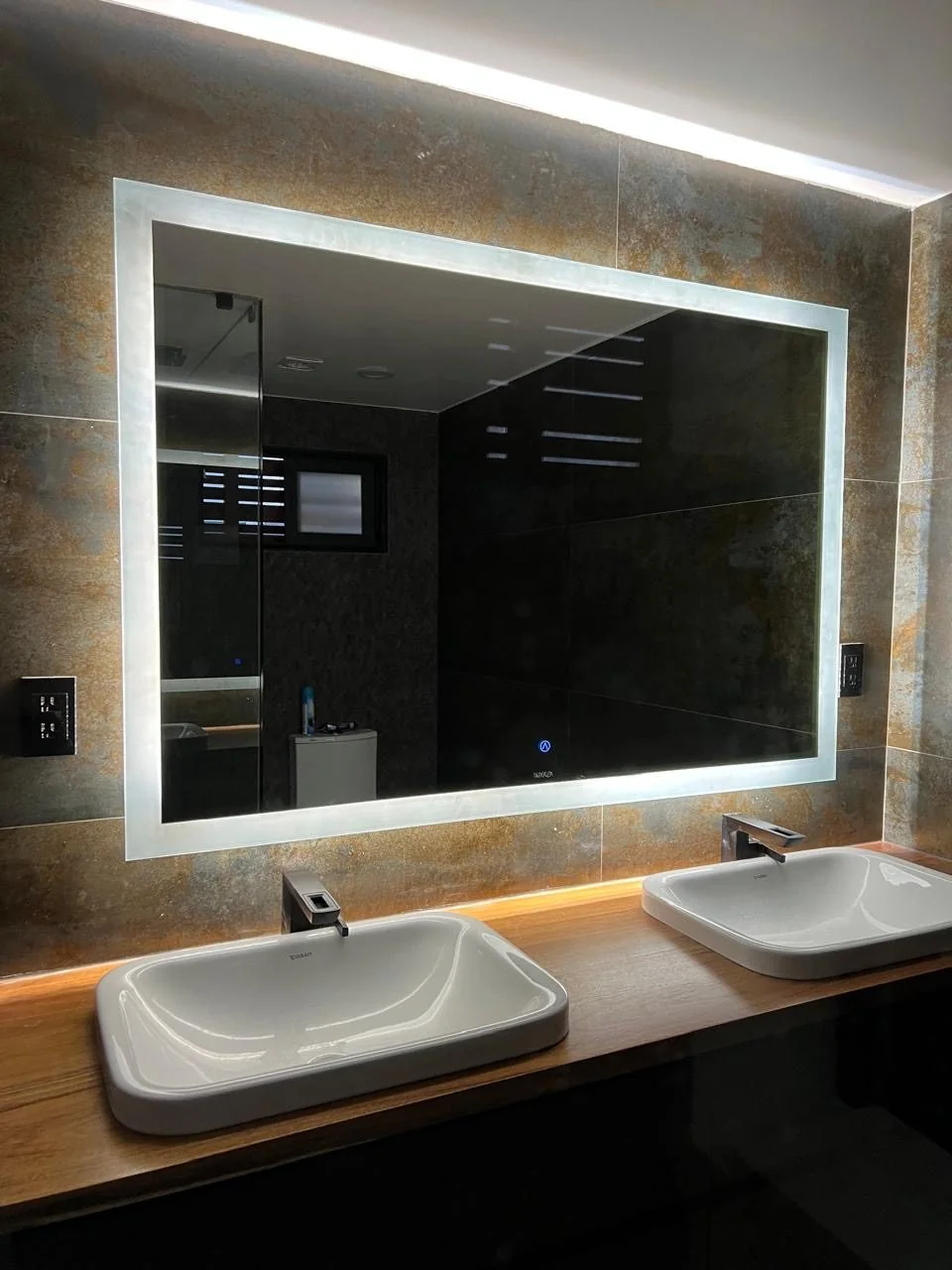 Baño con doble lavabo y espejos LED NAALA instalados en una casa