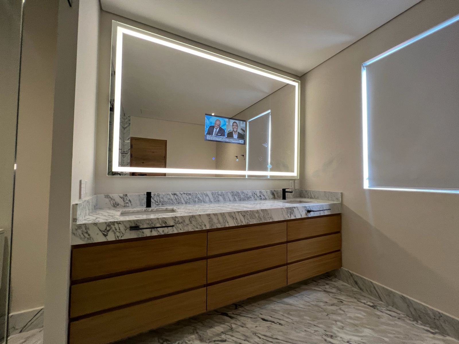 Espejo LED redondo NAALA instalado en baño de habitación de hotel